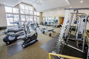 A gym with a variety of equipment including treadmills, stationary bikes, and weight machines.